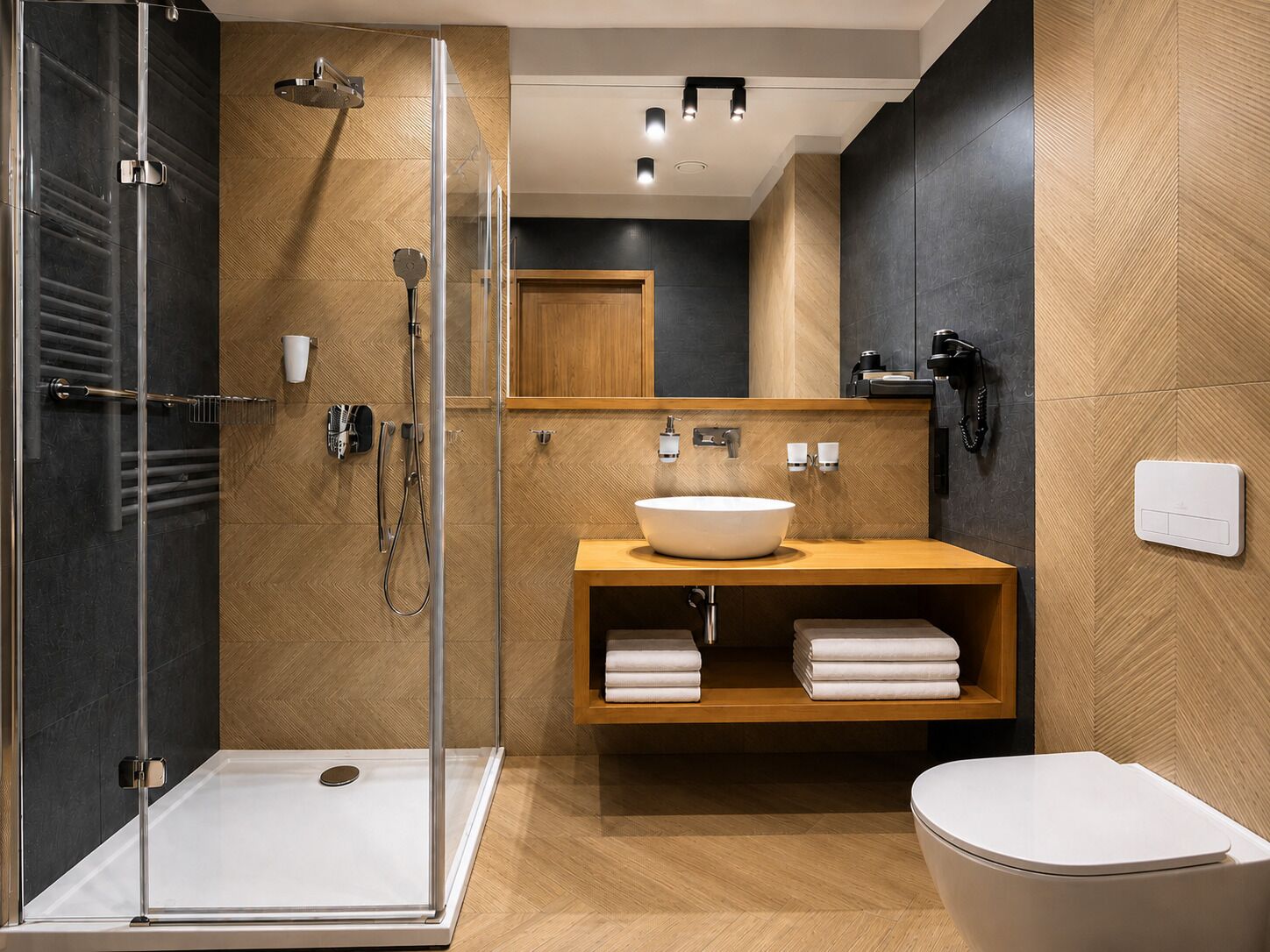 Un baño moderno con ducha acristalada, tocador de madera con lavamanos y un inodoro.