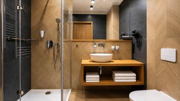 Un baño moderno con ducha acristalada, tocador de madera con lavamanos y un inodoro.
