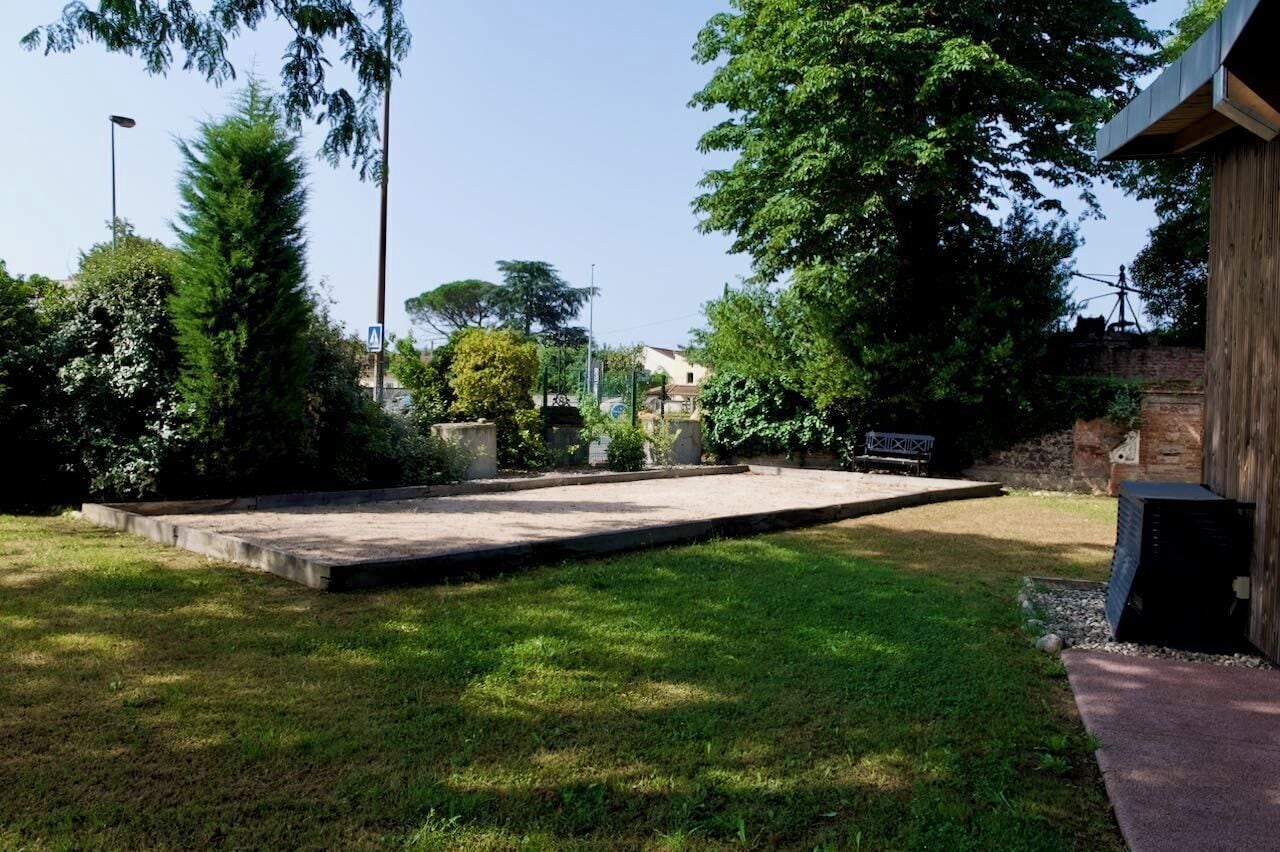 A well-maintained outdoor area with a concrete patio, surrounded by lush greenery and trees.
