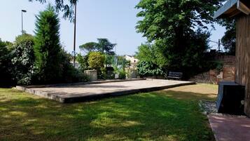 A well-maintained outdoor area with a concrete patio, surrounded by lush greenery and trees.