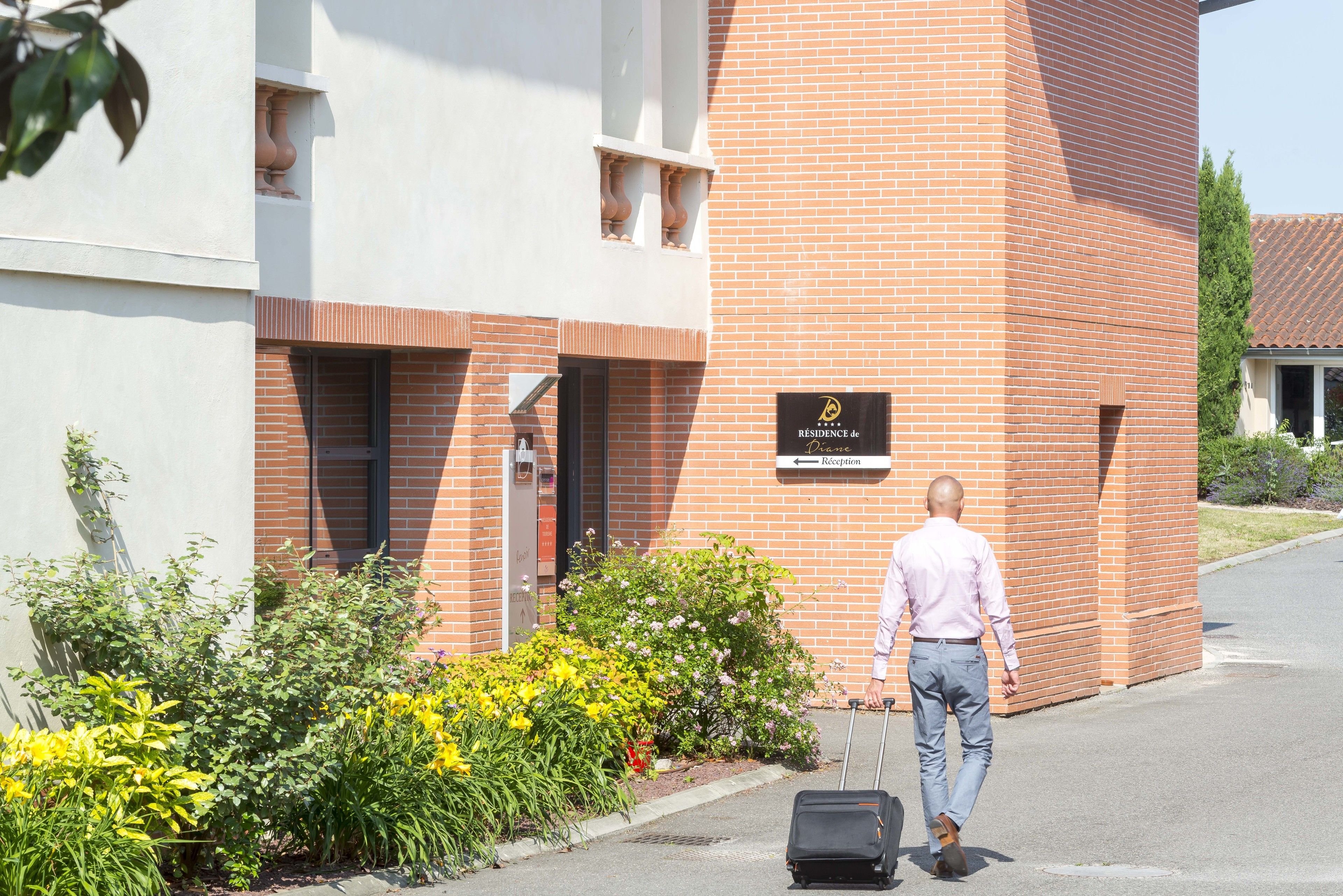 A man walking past a hotel with a sign reading "Residence de".