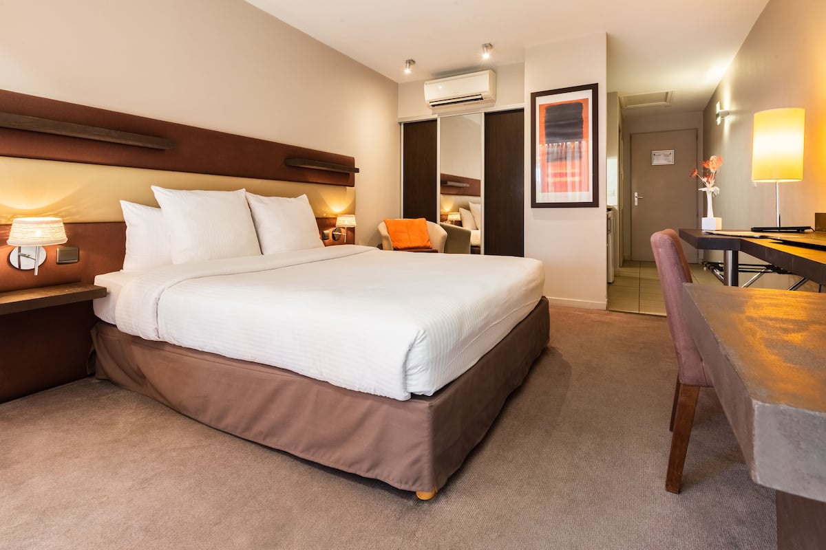 Une chambre d’hôtel avec un grand lit, un bureau, une chaise et un appareil de climatisation.