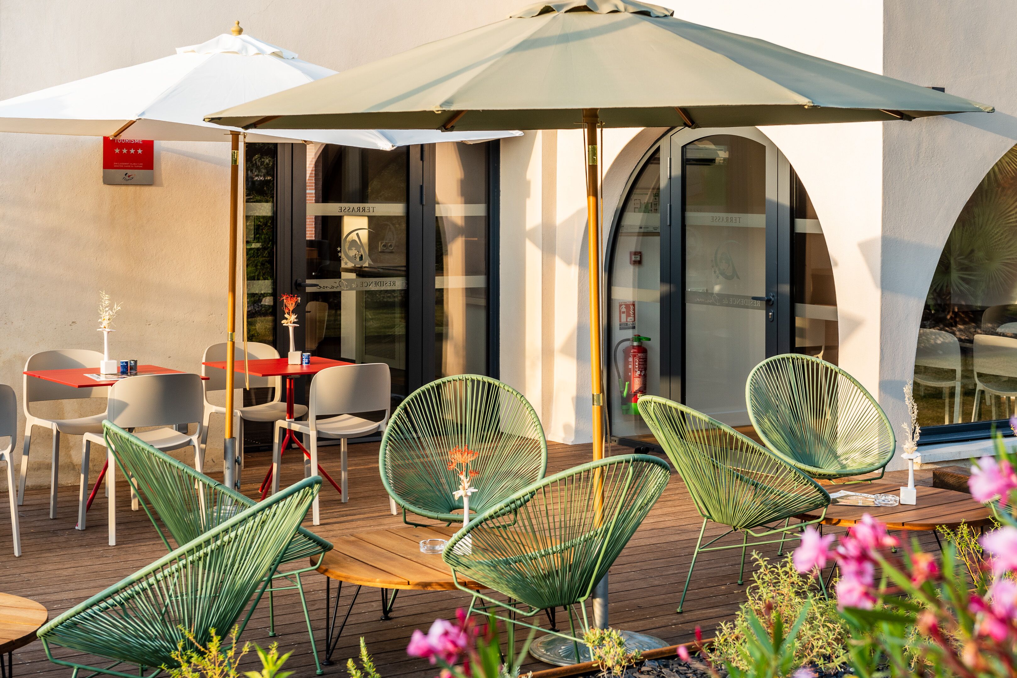 An outdoor seating area with green wire mesh chairs, a wooden table, and a white umbrella.
