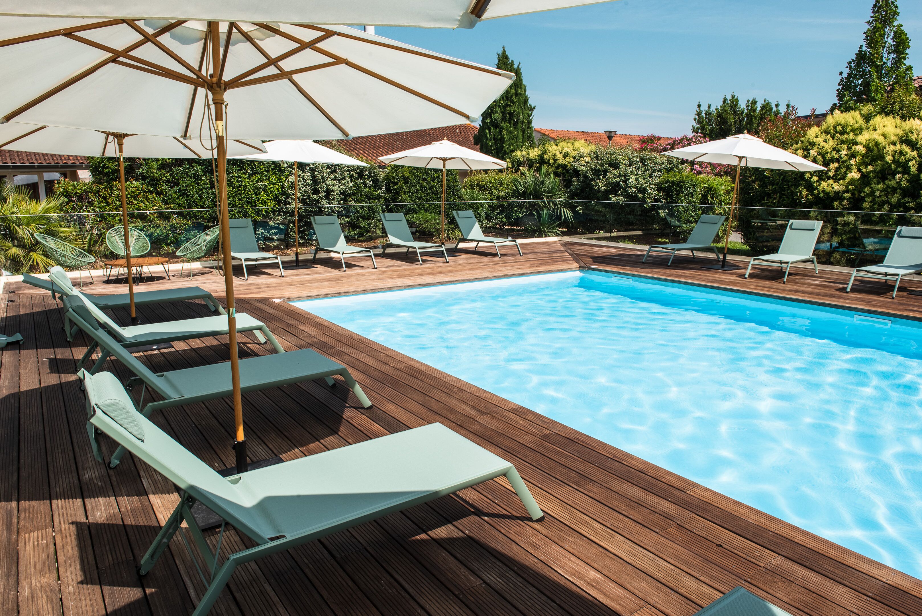 A wooden deck with a swimming pool, lounge chairs, and umbrellas.