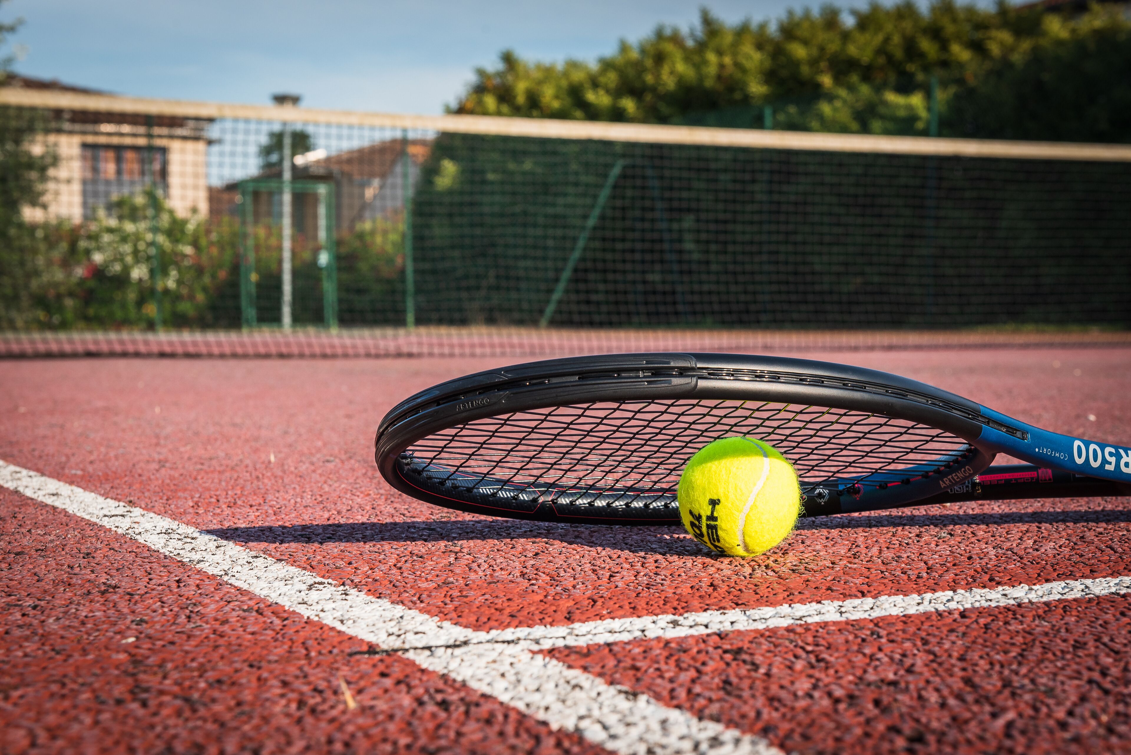 A tennis court with a tennis racket and ball.