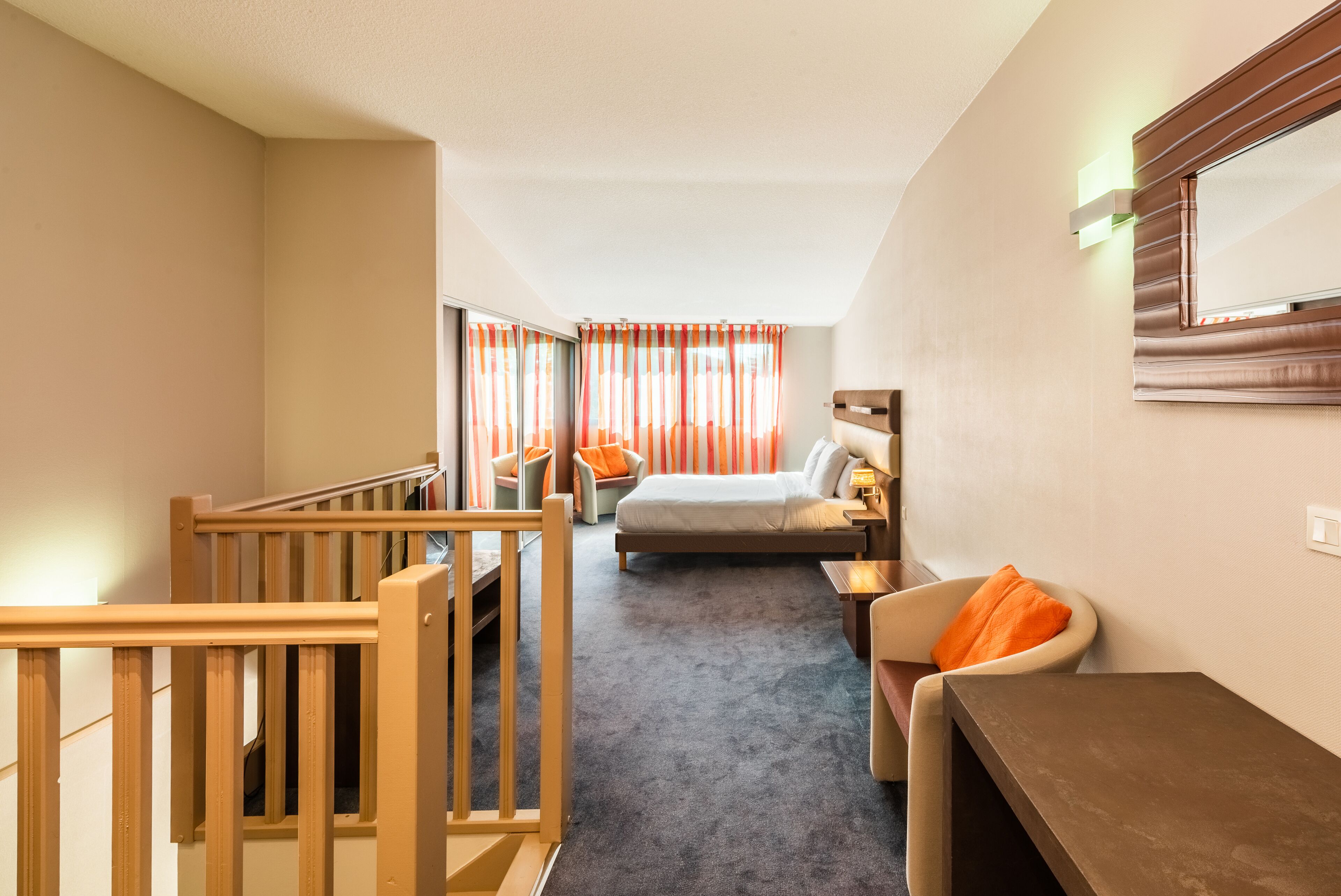 A hotel room with a bed, a desk, a chair, and a window with curtains.