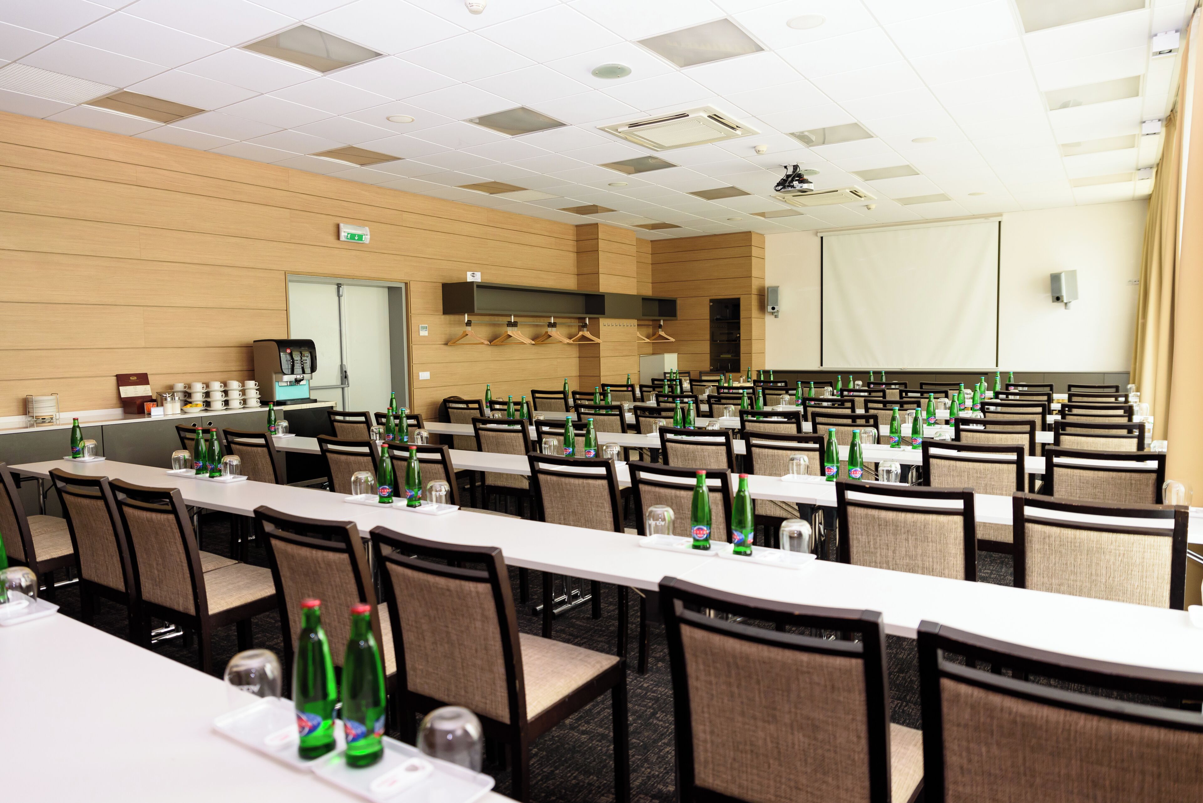 Un salón de conferencias con varias mesas, sillas y una estación de café.