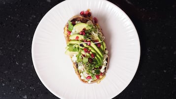 Un plato blanco con un sándwich sobre una encimera oscura.