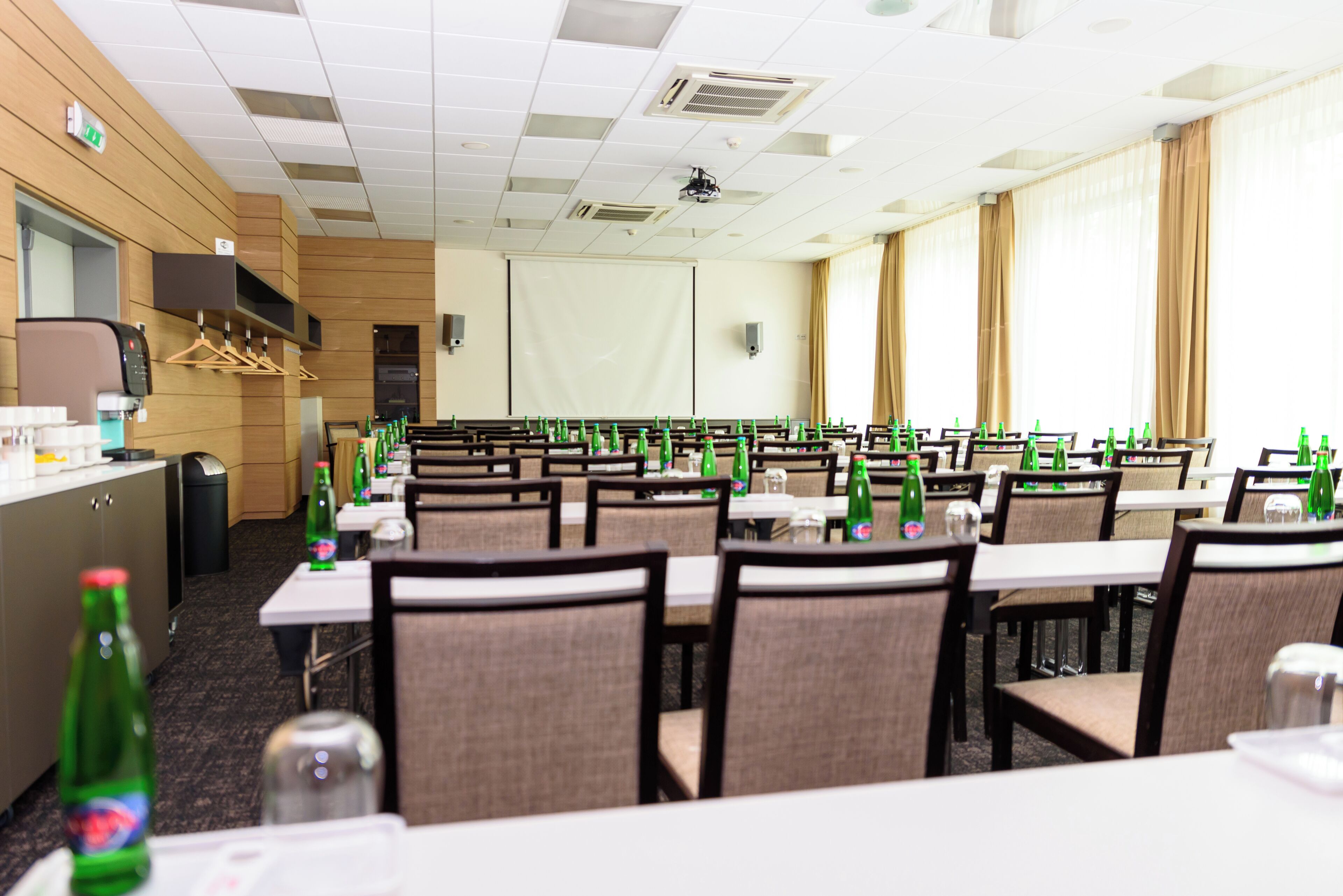 A conference room with tables, chairs, and a projector screen.