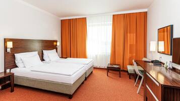 A hotel room with two beds, a desk, a chair, and a television.