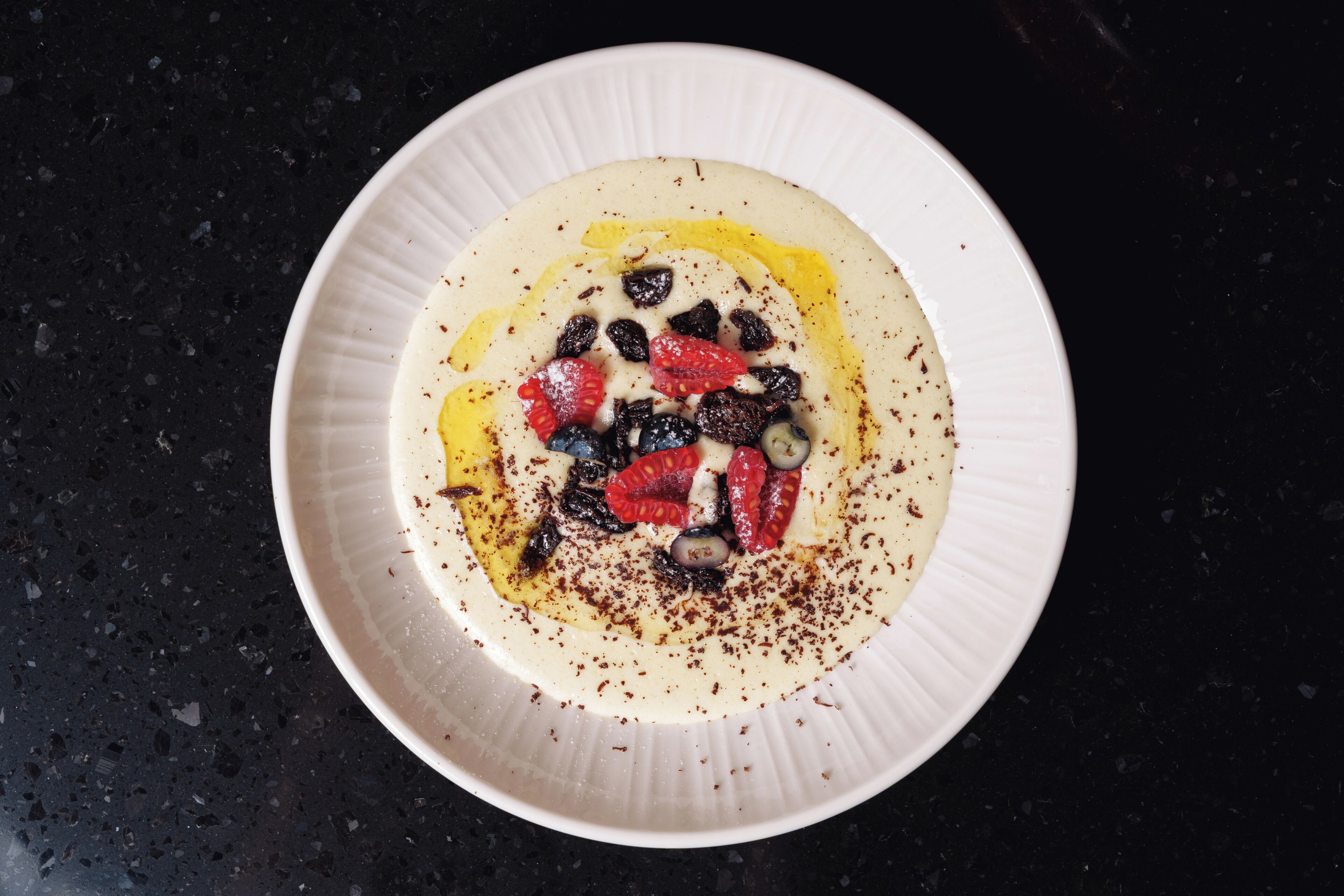 A white plate with a dessert on a dark countertop.