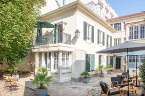 A courtyard with outdoor seating, a balcony, and potted plants. -  Hôtel Helzear Montparnasse (Paris)