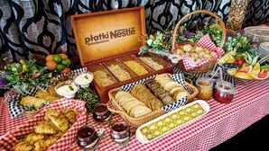 A buffet table with various food items, including pastries, fruits, and condiments, arranged on a checkered tablecloth. - NoBo Hotel (Lodz)
