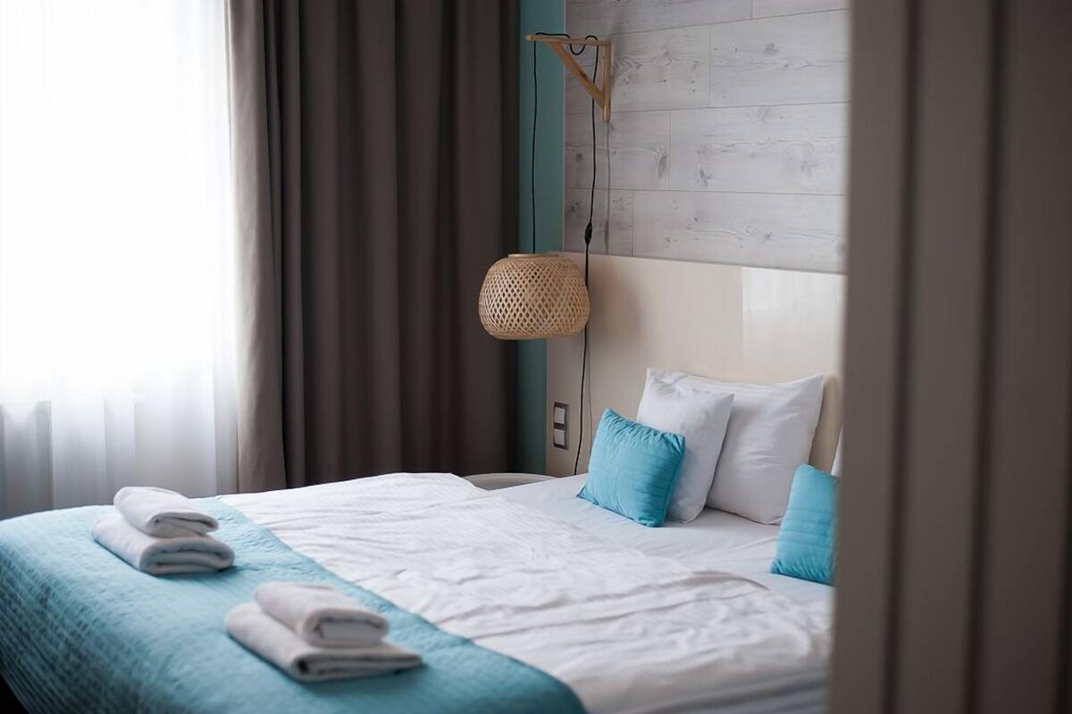 Una habitación de hotel con una cama, una lámpara de fibra y vistas al exterior.