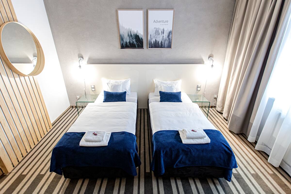 Habitación de hotel con dos camas, un espejo grande y dos cuadros en la pared.