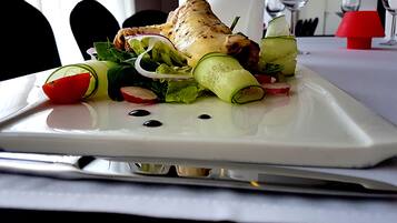 A white plate with a grilled chicken, salad, and vegetables.