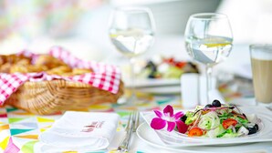A table set with a white plate of salad, two wine glasses, a basket of bread, and a cup of coffee. - NoBo Hotel (Lodz)
