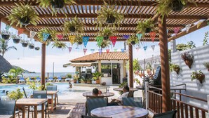 An outdoor seating area with tables and chairs, a pool, and potted plants. - Las Cabanas Del Capitan (Rincón de Guayabitos)