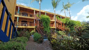 A multi-story building with a brick facade, outdoor staircases, and lush greenery. - Las Cabanas Del Capitan (Rincón de Guayabitos)