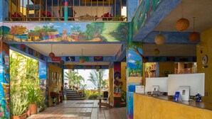A hotel lobby with a colorful mural, a staircase, and a reception desk. - Las Cabanas Del Capitan (Rincón de Guayabitos)