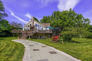 A two-story house with a stone chimney, a covered porch, and a stone pathway leading to the entrance.