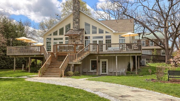 A large, two-story house with a stone chimney, a covered deck with outdoor seating, and a stone pathway leading to the entrance. - Battlefield Bed & Breakfast Inn (Gettysburg)