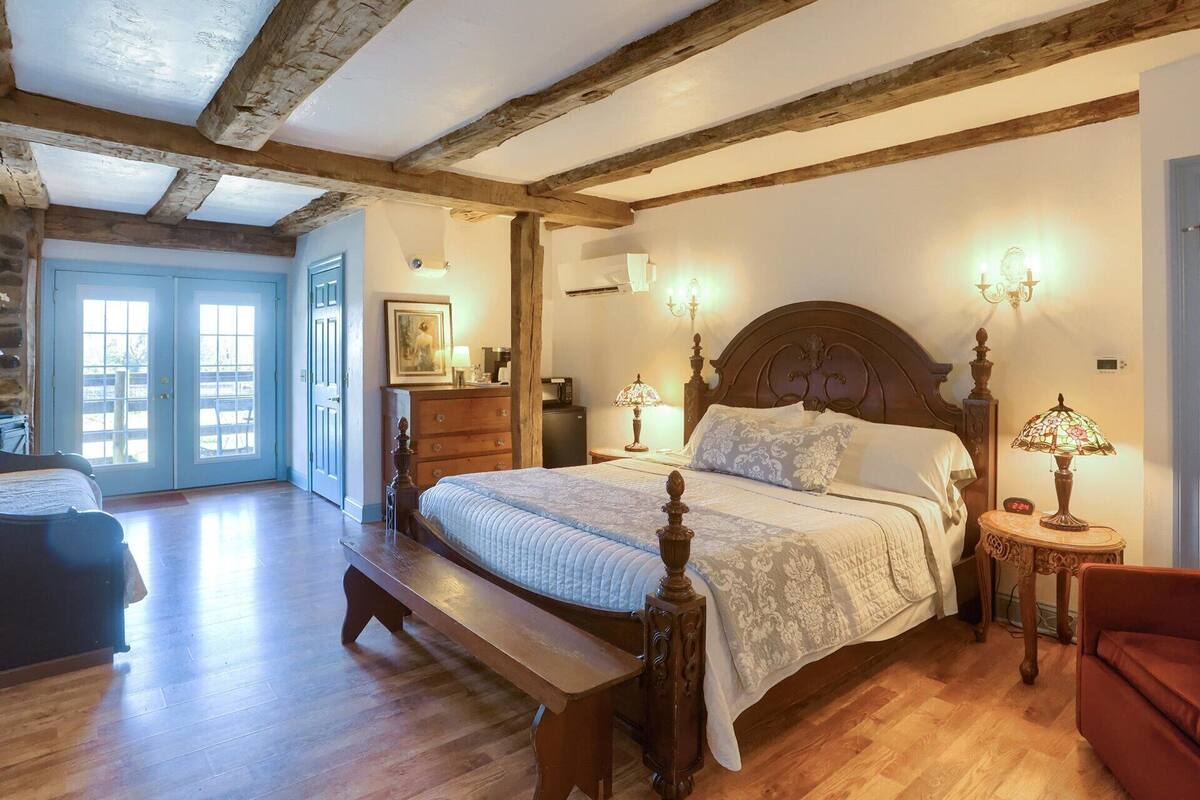 A bedroom with a wooden bed, a bench, a dresser, and a nightstand with a lamp.
