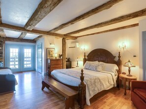 A bedroom with a wooden bed, a bench, a dresser, and a nightstand with a lamp.