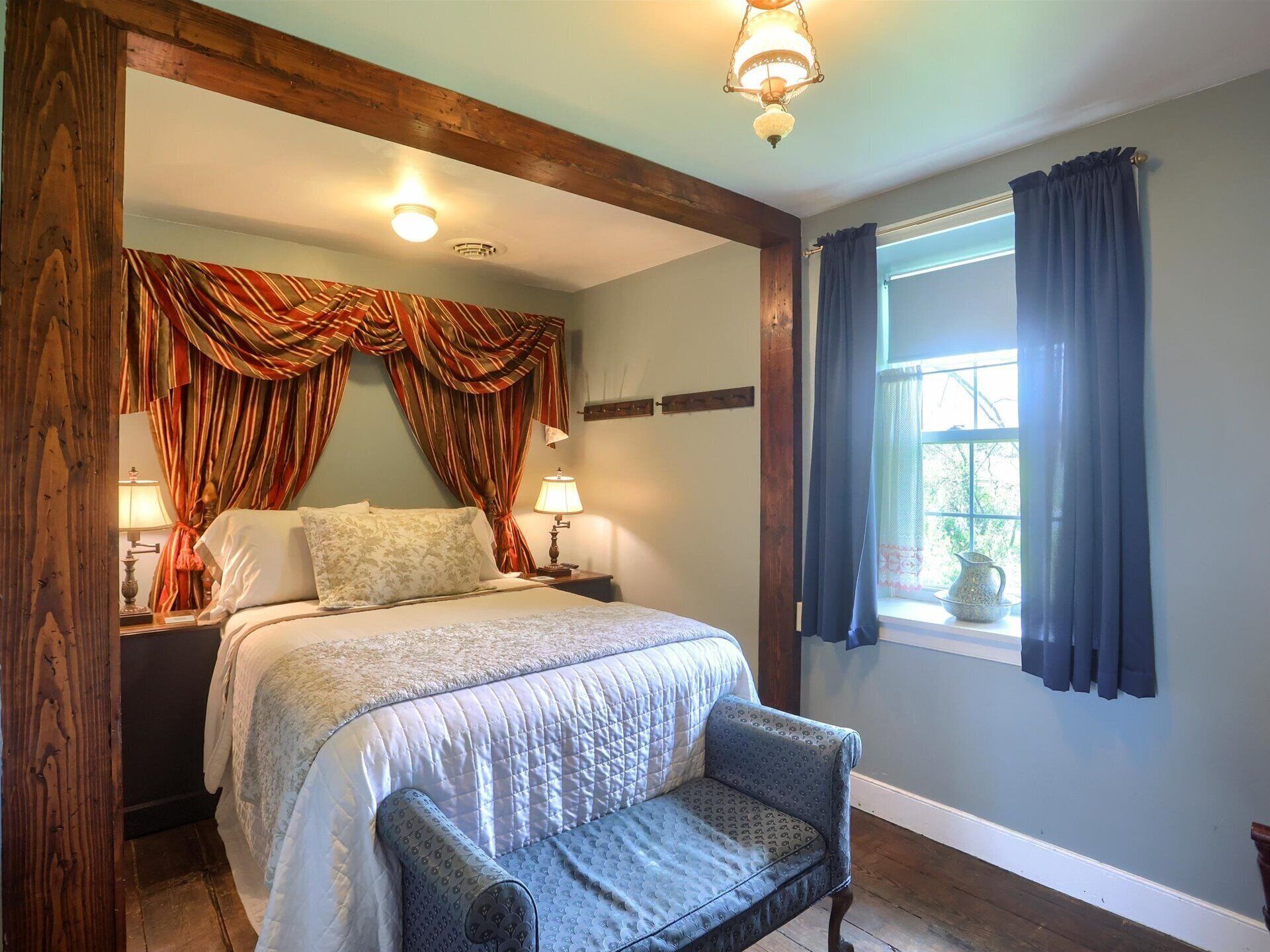 Une chambre à coucher avec un lit, deux lampes de chevet, une fenêtre avec des rideaux et une chaise.