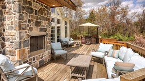 A stone exterior wall with a fireplace, wooden deck furniture, and a covered outdoor seating area. - Battlefield Bed & Breakfast Inn (Gettysburg)