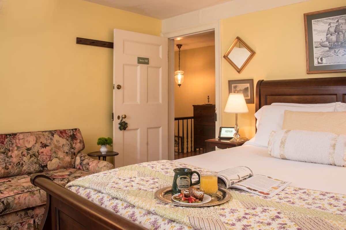 A hotel room with a bed, a floral sofa, a tray with breakfast, and a door labeled "Summer 2023".