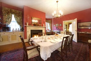 A dining room with a fireplace, a chandelier, and a dining table set for six. - Caldwell House Bed & Breakfast (Salisbury Mills)