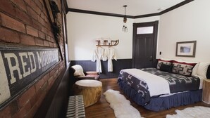 A bedroom with a bed, a bench, a coat rack, and a door. - Teller House (Silverton)