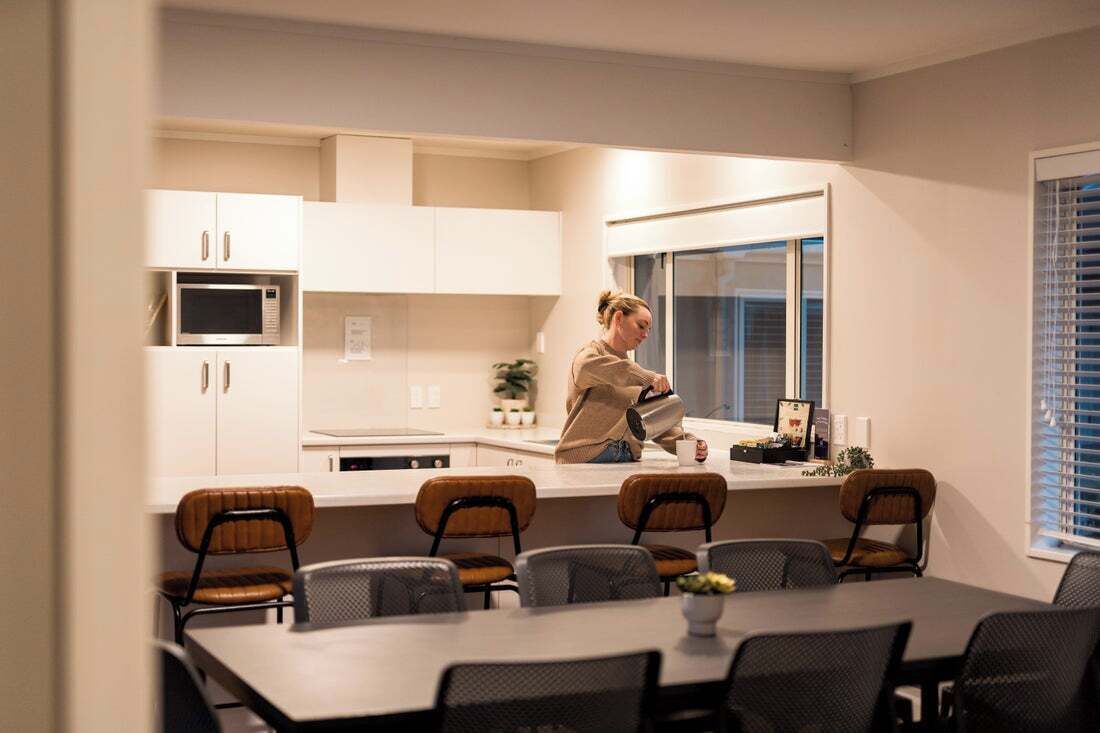 A modern kitchen with white cabinets, a microwave, and a dining area with a table and chairs.