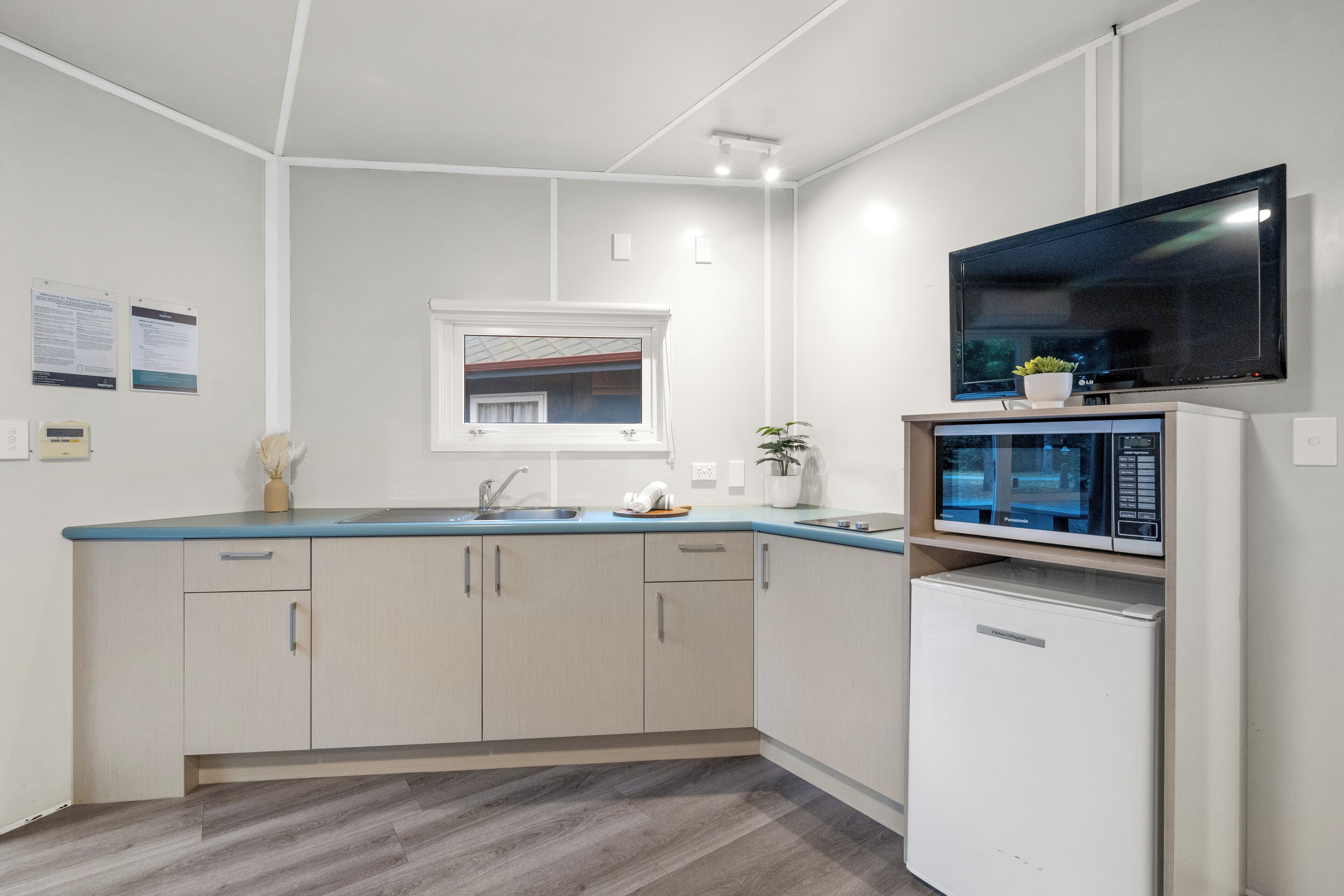 Una cocina moderna con microondas integrado, un fregadero y una ventana sobre la encimera.