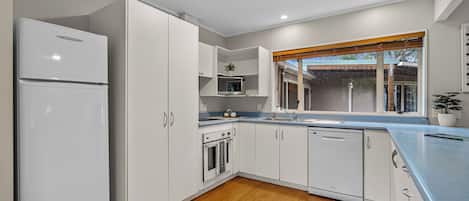 A modern kitchen with white cabinets, a built-in oven, microwave, and dishwasher.