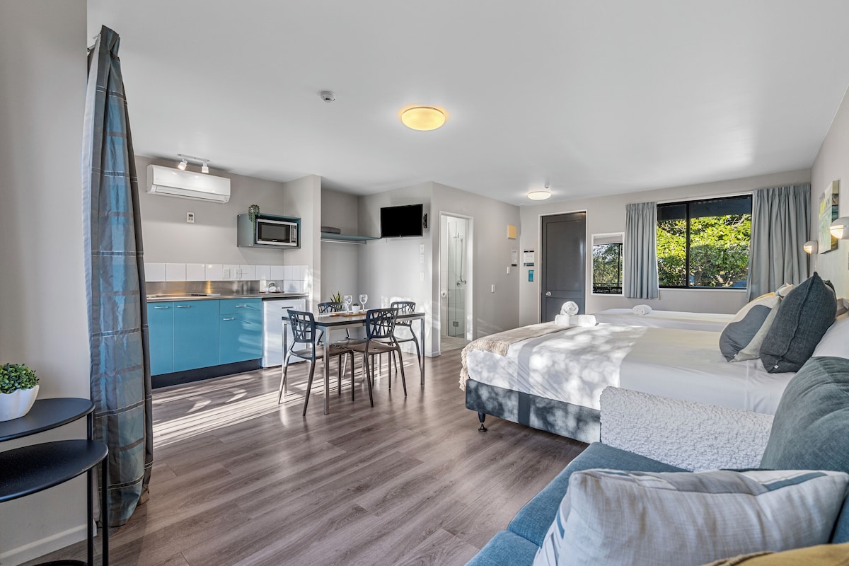 Een modern appartement met keuken, eethoek en een slaapkamer met groot bed en een slaapbank.