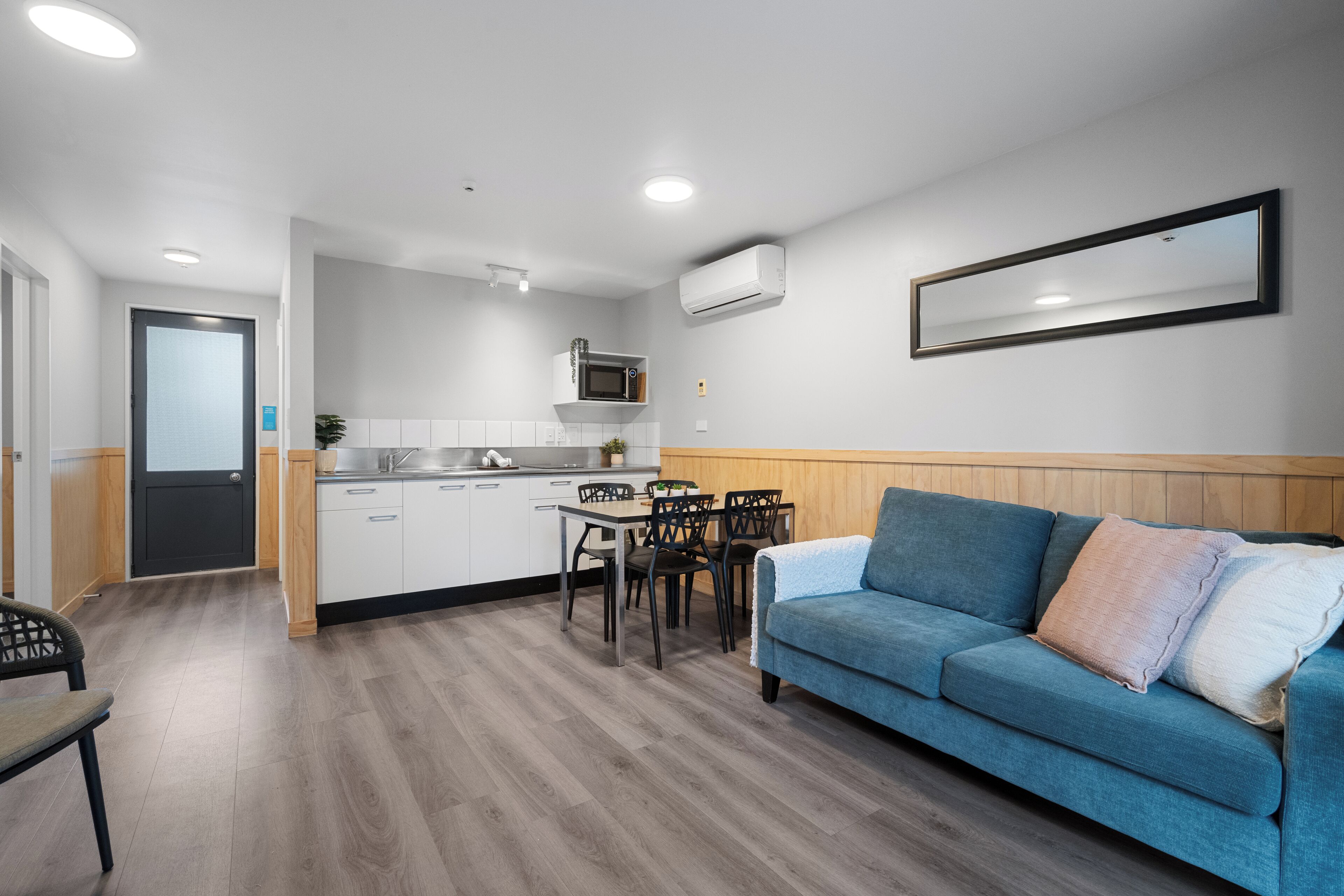 Una cocina moderna con armarios blancos, microondas y comedor con mesa y sillas.
