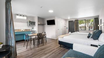 Una habitación de hotel moderna con kitchenette, zona de comedor y dos camas.