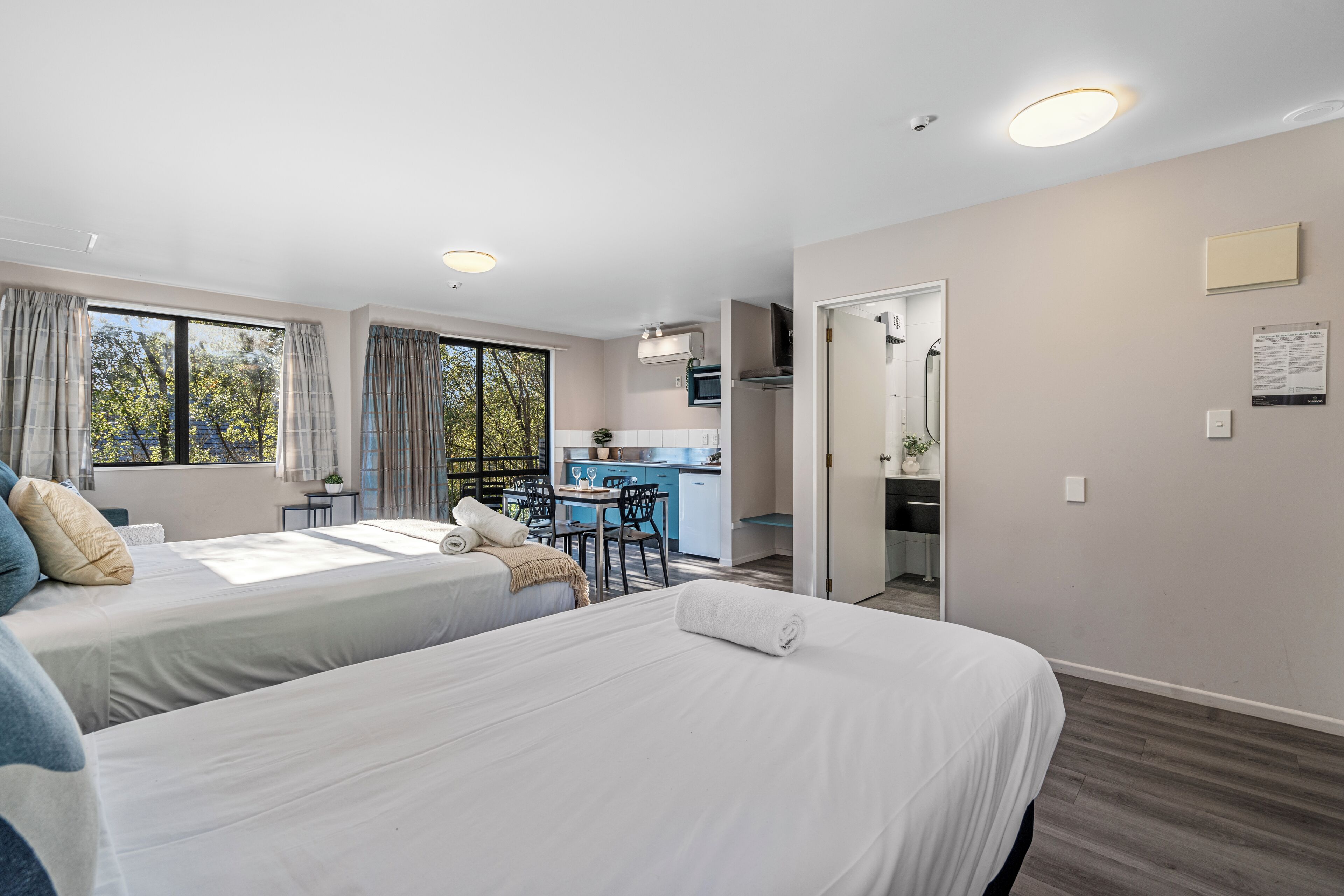 Habitació d'hotel amb dos llits, una cuineta i zona de menjador.