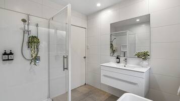 A modern bathroom with a glass-enclosed shower, a white vanity with a mirror, and a bathtub.