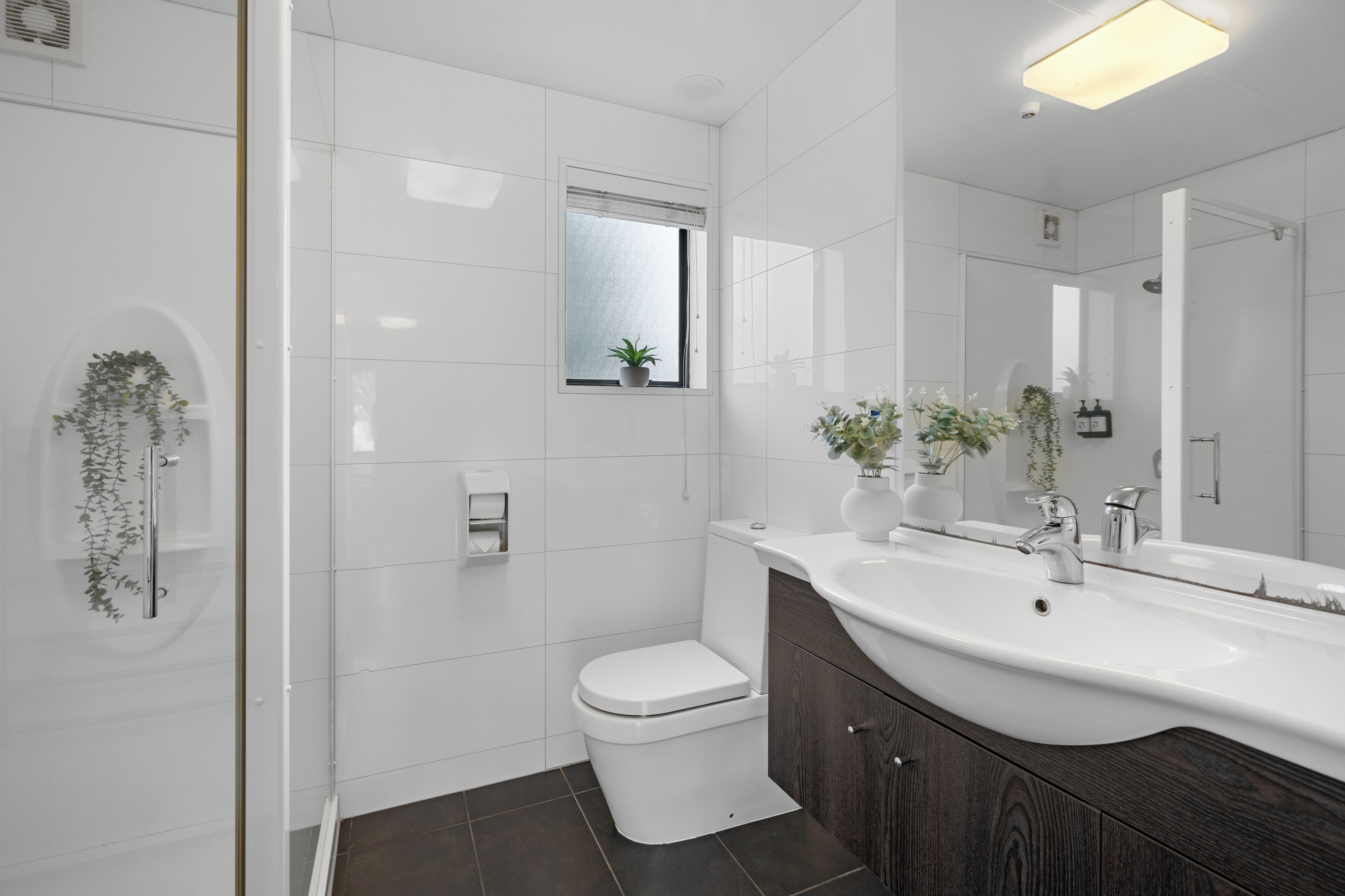 A modern bathroom with a white toilet, a large sink, and a mirror.