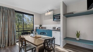 A modern kitchen with a dining area, large windows, and a built-in microwave. - Tasman Holiday Parks - Christchurch (Christchurch)