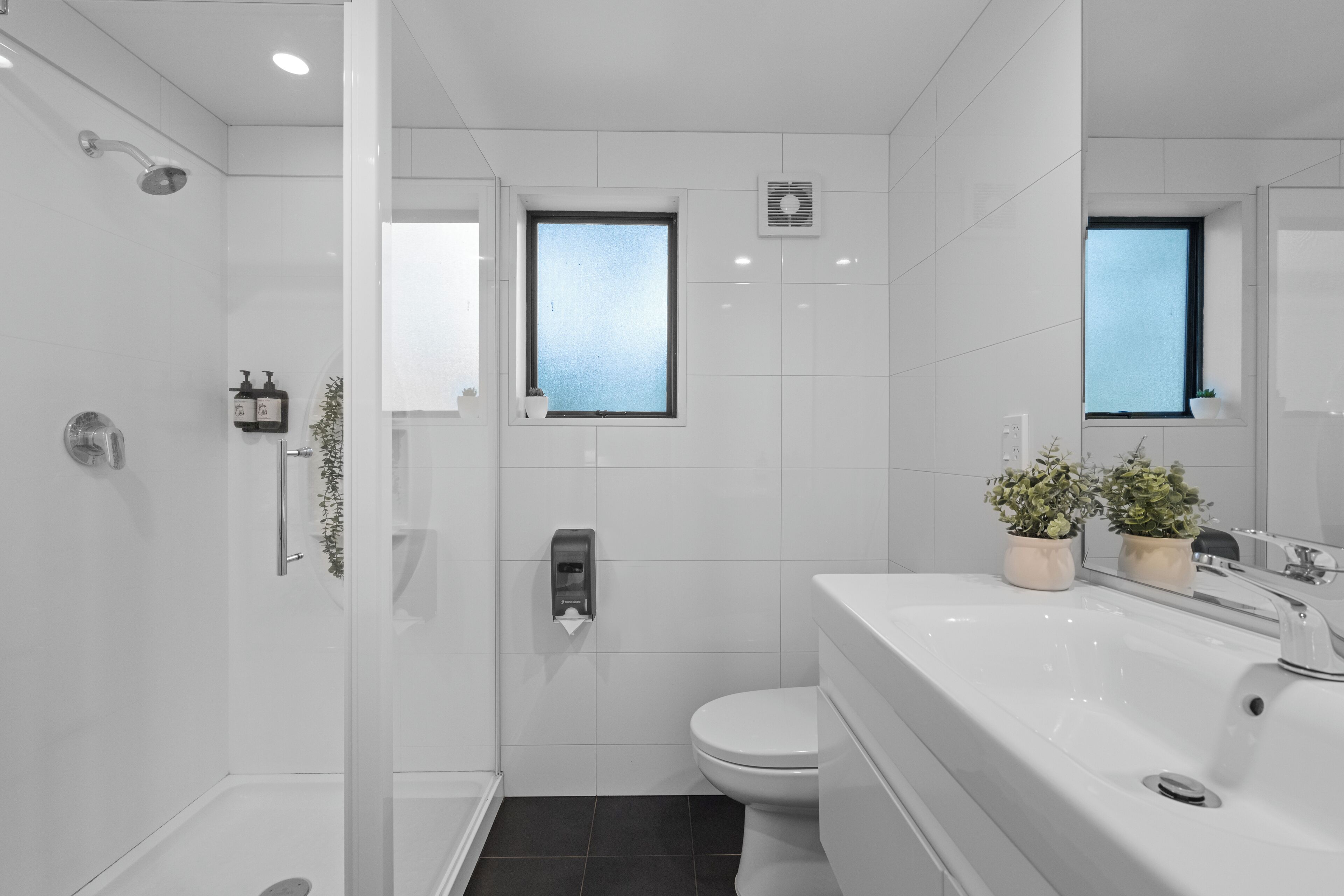 Un baño moderno con cabina de ducha de vidrio, inodoro y lavabo con espejo.