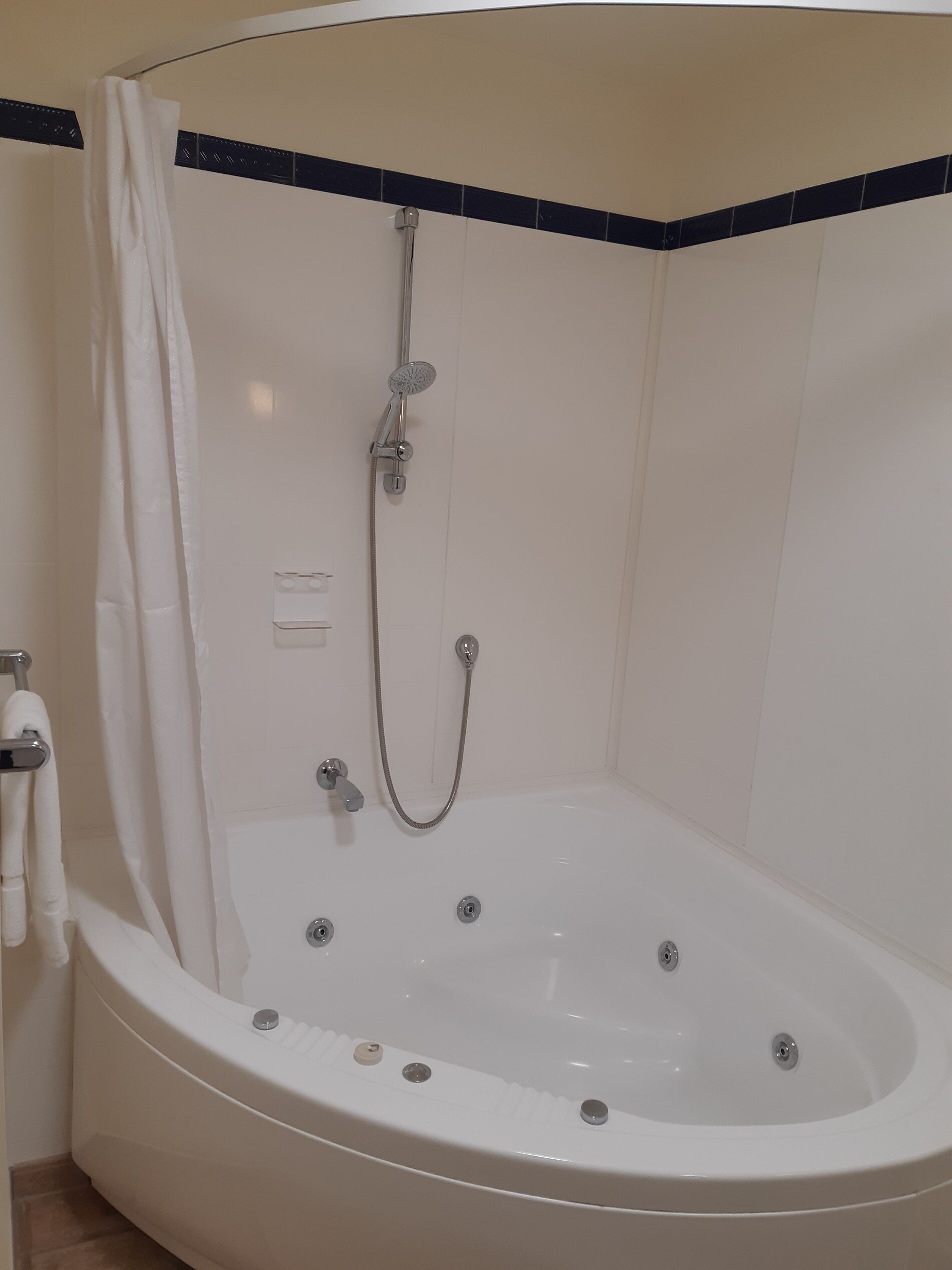 A white bathtub with a showerhead and control knobs, a towel rack, and a curtain.