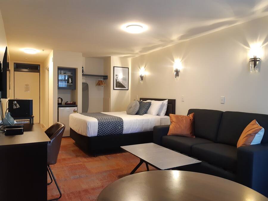 Une chambre d’hôtel de taille réduite, comprenant un lit, un canapé, un bureau et une kitchenette.