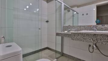 A modern bathroom with a glass shower enclosure, a granite countertop sink, and a toilet.