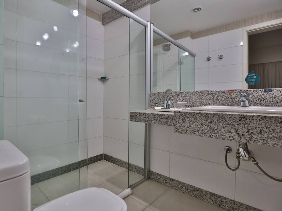 A modern bathroom with a glass shower enclosure, a granite countertop sink, and a toilet.
