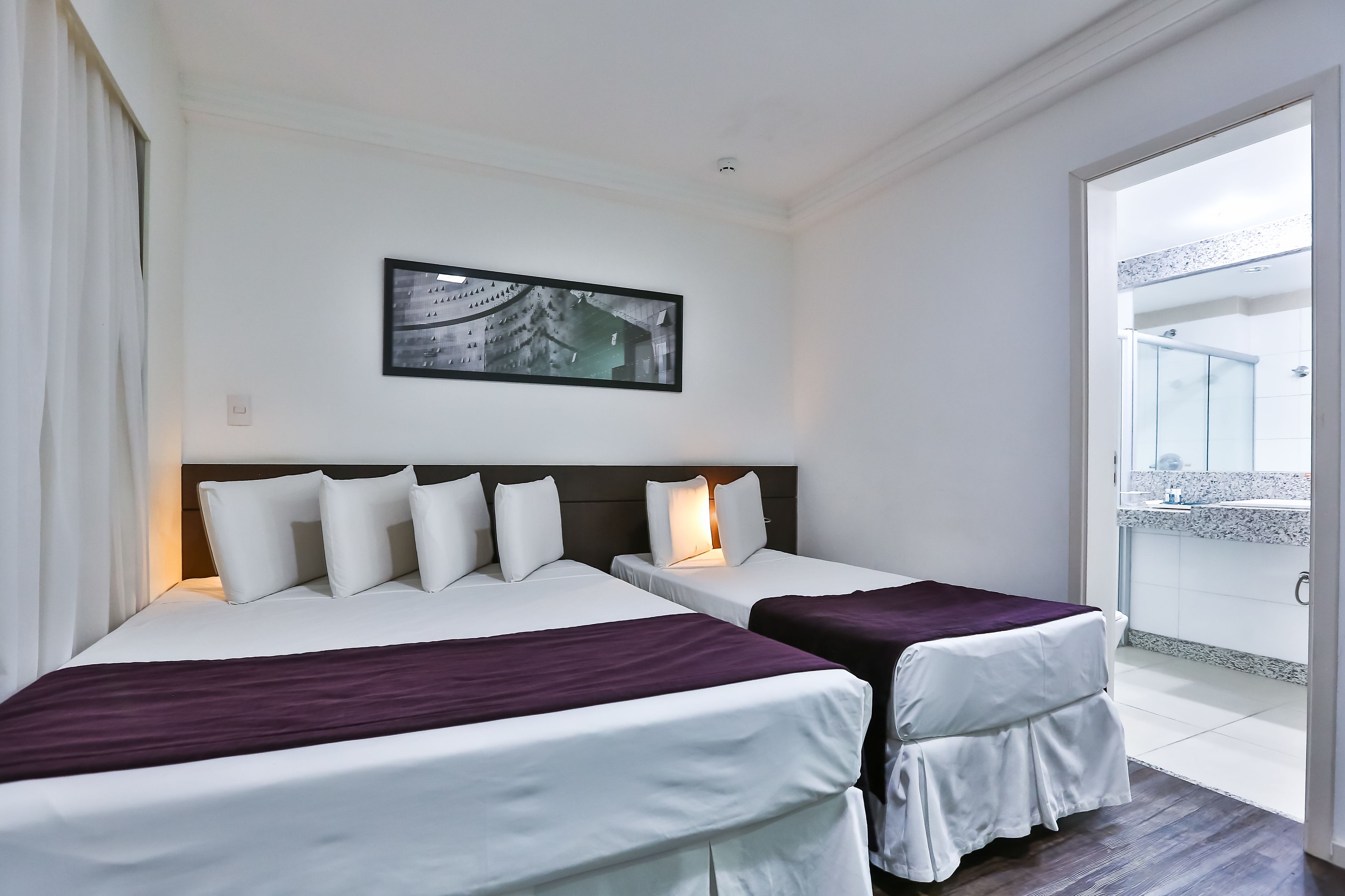 Une chambre d’hôtel avec deux lits, un balcon et un tableau encadré au mur.