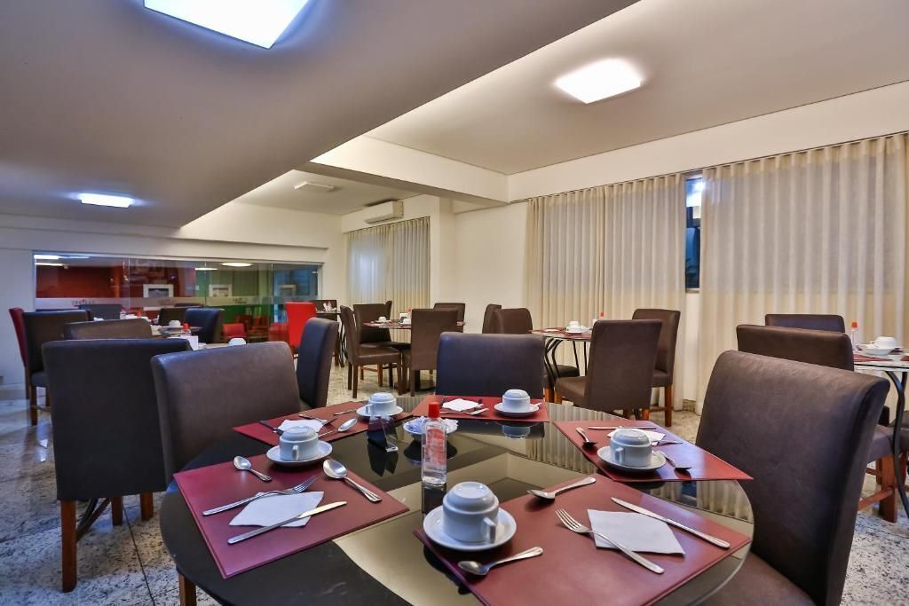 A hotel dining area with round tables, chairs, and a glass partition.